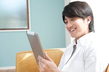 Asyalı adamın elinde tablet bilgisayar var