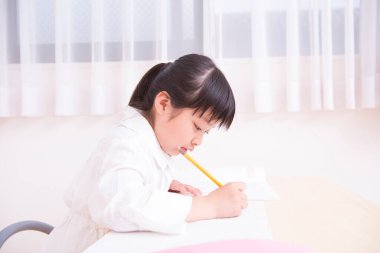 Küçük Asyalı kız ödevini yapıyor. 