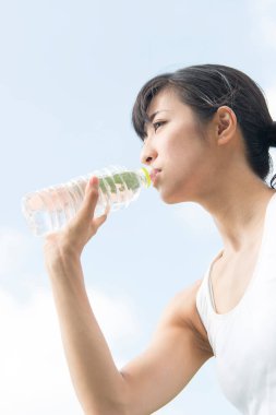 Yaz parkında koşu yaparken su içen güzel Japon kadın. 