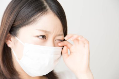 Soluk maskeli hasta bir Asyalı kadının portresi beyaza izole edilmiş.