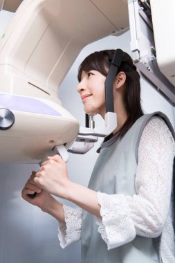 Kadın hasta dişçi tomografisi yapıyor. Dişlerinin röntgenini çeken kadın ortodontik röntgen makinesinin yardımıyla klinikte.