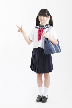 Okul üniformalı güzel bir öğrencinin portresi beyaz arkaplanı işaret ediyor.