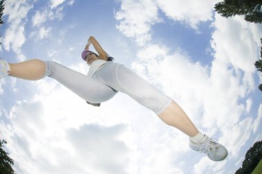 Mavi arka planda havaya atlayan genç bir kadın. 