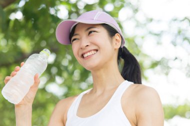 Yaz parkında koşu yaparken su içen güzel Japon kadın. 