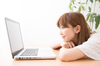 Evde dizüstü bilgisayarı olan gülümseyen güzel bir Japon kadın.