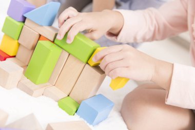 Küçük sevimli Asyalı kız tahta oyuncak bloklarıyla oynuyor.