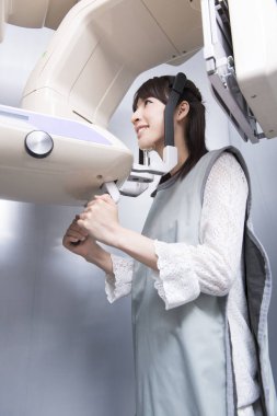 Kadın hasta dişçi tomografisi yapıyor. Dişlerinin röntgenini çeken kadın ortodontik röntgen makinesinin yardımıyla klinikte.