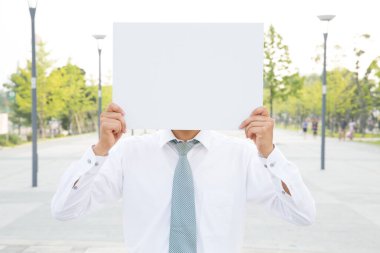 Beyaz takım elbiseli, açık havada boş afişi olan bir iş adamı.