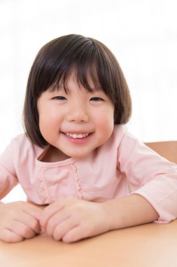 Kameraya gülümseyen Asyalı küçük kız.