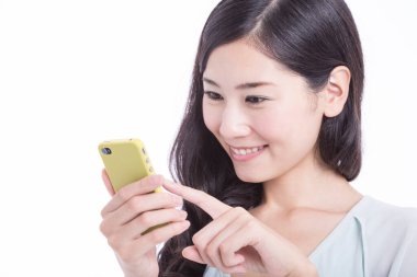 Beyaz arka planda izole edilmiş akıllı telefon kullanan gülümseyen genç Asyalı kadın. Stüdyo çekimi