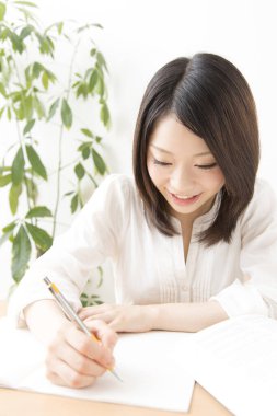 Genç Asyalı kadın bir şeyler yazıyor.