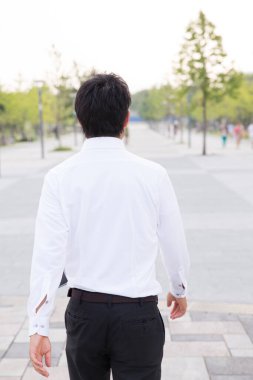 Şehir caddesinde yürüyen genç işadamının arka görüntüsü