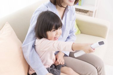 Asyalı bir aile kanepede televizyon izliyor.