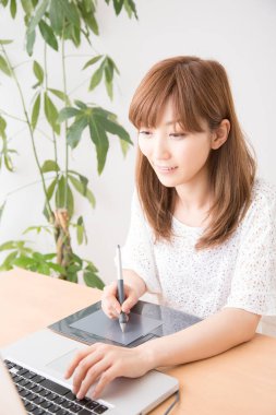 Dizüstü bilgisayar ve grafik tableti ile çalışan kadın grafik tasarımcısı