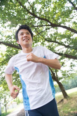 Sportif Japon adam yaz parkında koşuyor. 