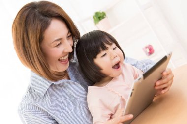 Tablet kullanan Asyalı bir kadın ve bir çocuk.