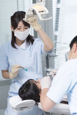 Genç Asyalı kadın doktor ve dişçi kadın hasta ile çalışıyor. 