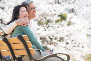 Güzel Asyalı olgun çifti ağaçlarla parka kapatın.