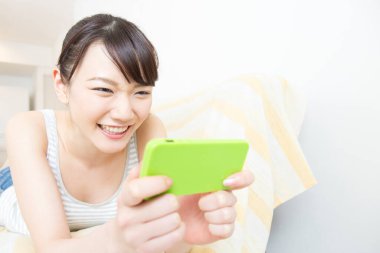 Evde cep telefonu kullanan genç bir kadın.