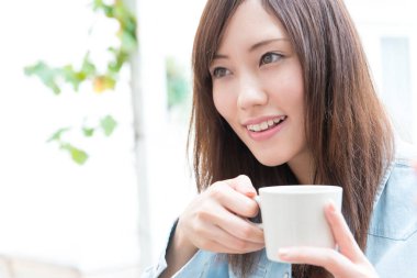 Sıcak kahve içen Asyalı kadını kapat.