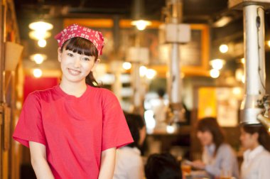 Genç Asyalı garson kız gülümsüyor.