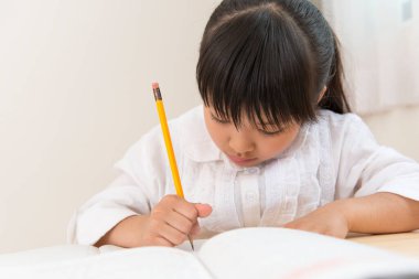 Küçük Asyalı kız ödevini yapıyor. 