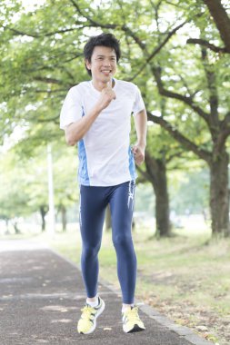 Sportif Japon adam yaz parkında koşuyor. 