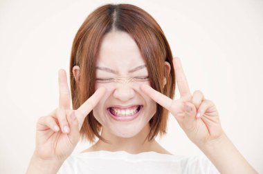 Güzel genç Japon kadının portresi. Yüzünü buruşturuyor ve bej arka planda Ziyaretçi işaretleri gösteriyor.