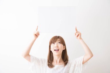 Asyalı genç bir kadın elinde beyaz bir tahta tutuyor.