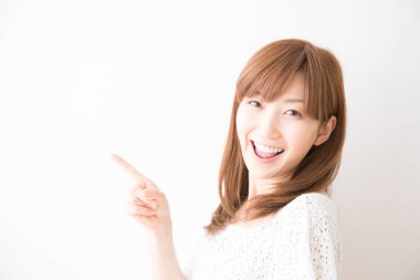 Asyalı kadın beyaz arka planda eli olan bir şey gösteriyor.