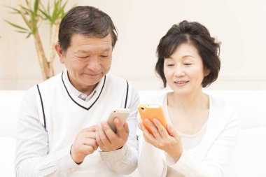 Yetişkin Asyalı çifti telefonları kullanarak kapatın.