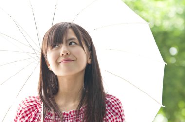 Yaz parkında şemsiyeli güzel bir Asyalı genç kadın.