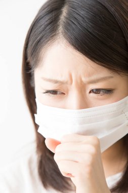 Soluk maskeli hasta bir Asyalı kadının portresi beyaza izole edilmiş.