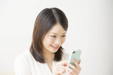 Beyaz üzerine izole edilmiş akıllı telefon kullanan güzel Asyalı bir kadının portresi.
