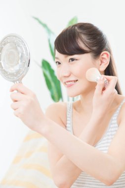 Makyaj yapmak için makyaj fırçası kullanan genç bir kadın.