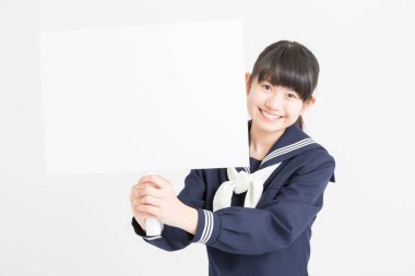 Okul üniformalı güzel bir öğrencinin portresi beyaz arka planda boş bir poster tutuyor.