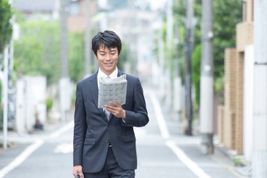 Gazetesi olan bir işadamı sokakta yürüyor.