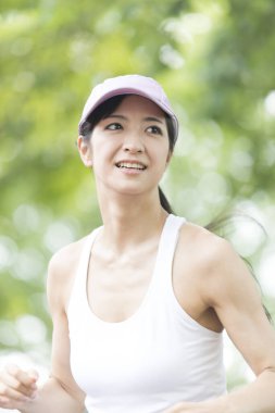 Spor yapan Japon kadın yaz parkında koşuyor. 