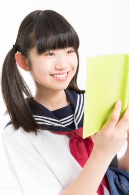 Okul üniformalı, beyaz arkaplan üzerine kitabı olan güzel bir öğrencinin portresi.