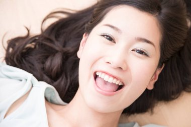 Kadın kameraya gülümsüyor, yatakta yatıyor. 