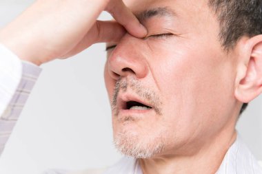 Beyaz arka planda acıdan muzdarip olgun Asyalı adamın portresi.