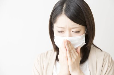 Soluk maskeli hasta bir Asyalı kadının portresi beyaza izole edilmiş.