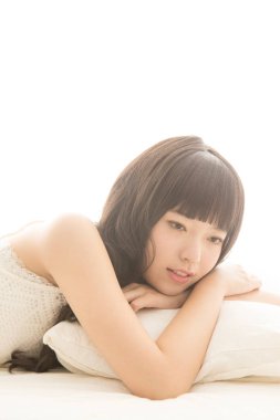 Genç Asyalı kadın yatakta yatıyor.