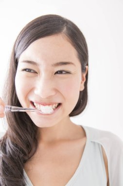 Diş fırçasıyla diş temizleyen genç Asyalı kadın.