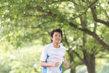 Sportif Japon adam yaz parkında koşuyor. 