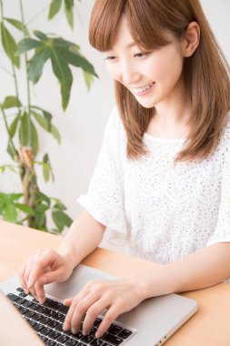 Evde dizüstü bilgisayarı olan gülümseyen güzel bir Japon kadın.