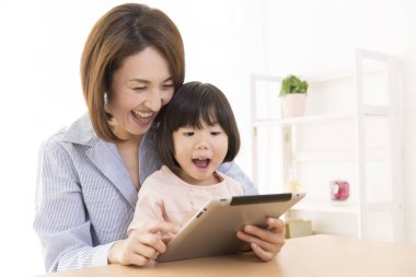 Tablet kullanan Asyalı bir kadın ve bir çocuk.