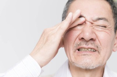 Beyaz arka planda acıdan muzdarip olgun Asyalı adamın portresi.