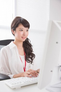 Ofiste bilgisayarla çalışan genç bir kadın.