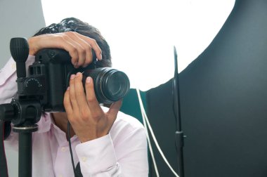 Asyalı yakışıklı erkek fotoğrafçı DSLR kamerasını elinde tutuyor. 
